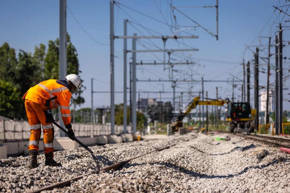 Un compagnon étale le Ballast autour des voies